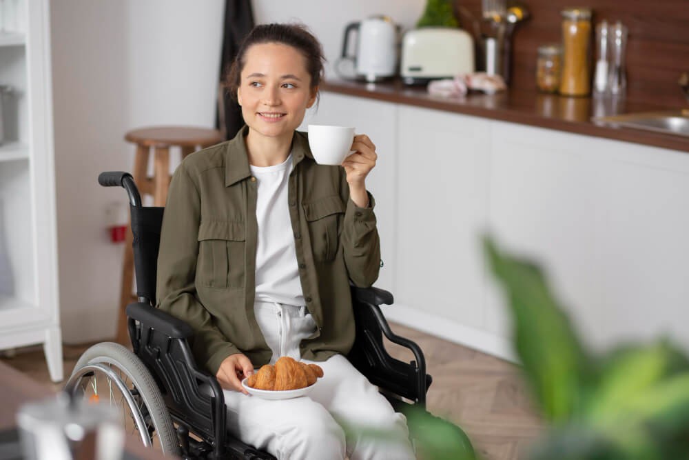 participant in a wheelchair enjoying a coffee in an accessible kitchen