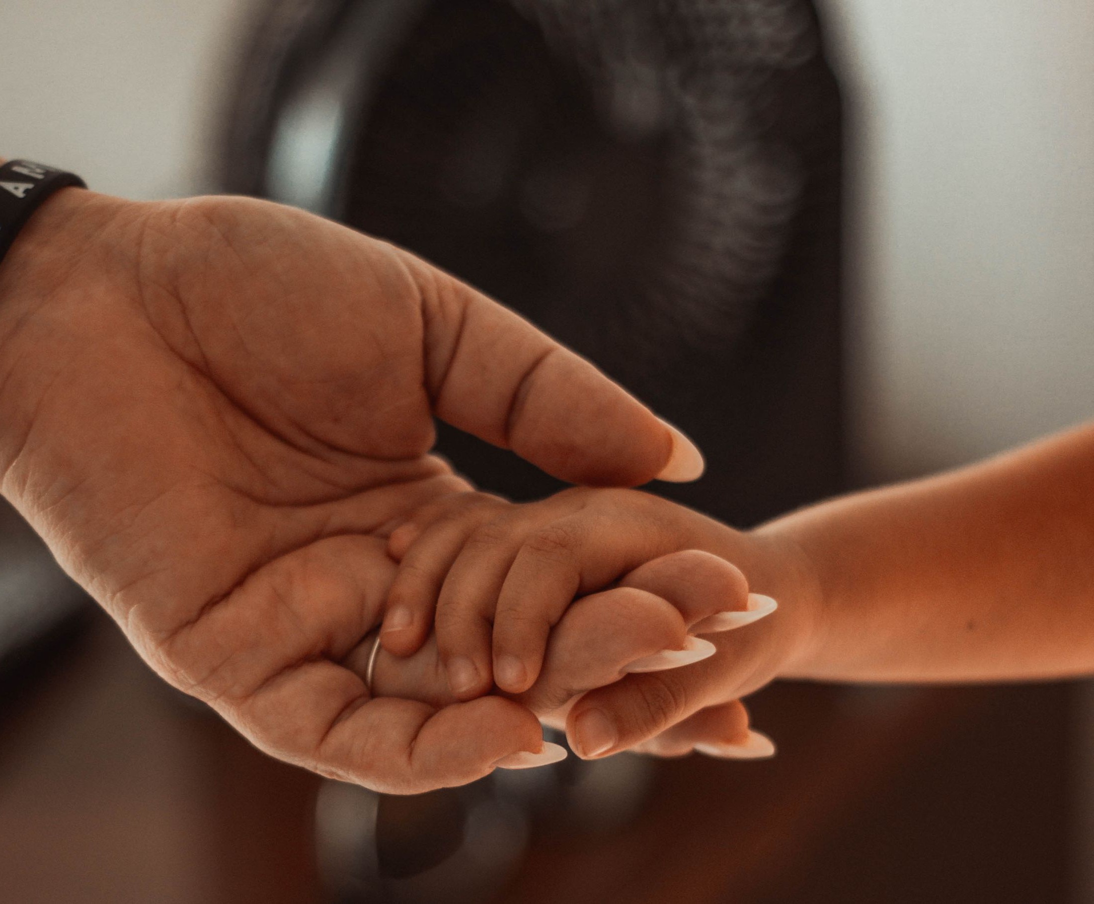 Emotional close-up of a parent and child holding hands, showing connection and love.